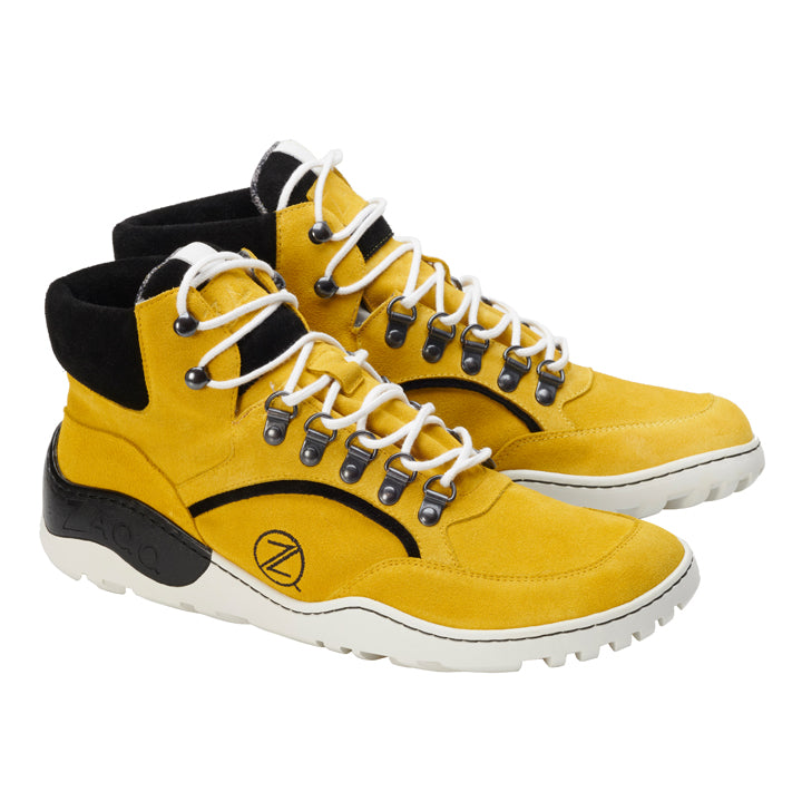 Ein Paar wasserdichte TREQ Yellow Wildleder-Wanderstiefel von ZAQQ mit weißen Schnürsenkeln, schwarzem Besatz und strapazierfähigen Gummisohlen. Inspiriert von Barfußschuh-Designs verfügen diese Stiefel über Metallösen und Ziernähte sowie ein markantes kreisförmiges Motiv an der Seite.