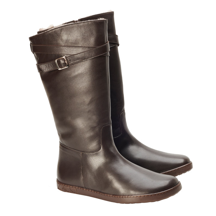 Ein Paar hohe ATTRAQT Winter Brown-Stiefel aus dunkelbraunem Leder von ZAQQ mit dekorativen Riemen und Schnallen am oberen Rand und einer flachen Sohle für zusätzlichen Komfort.