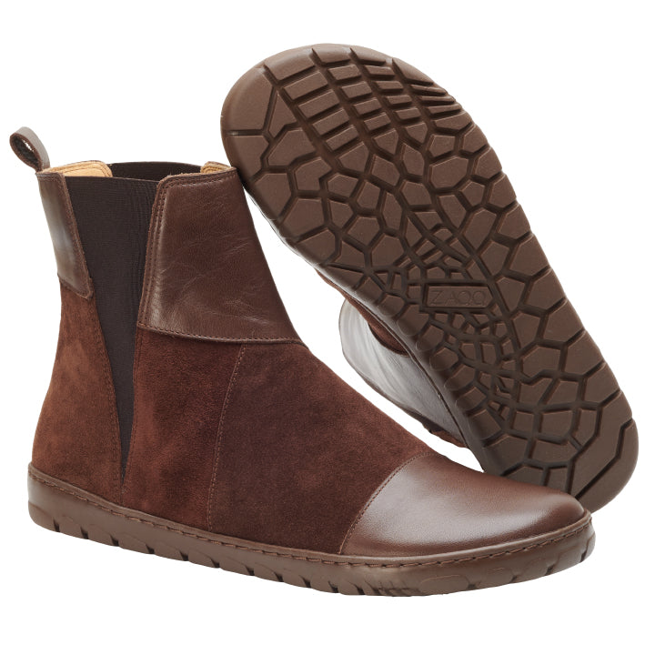 Wir präsentieren die ZAQQ PETAQ Brown Stiefeletten. Diese Stiefel im Chelsea-Boot-Stil sind aus einer Kombination aus Leder und Wildleder gefertigt und verfügen über elastische Seitenteile und eine strapazierfähige Gummisohle. Ein Stiefel steht aufrecht, während der andere mit der Sohle nach oben geklappt ist, um sein einzigartiges sechseckiges Profilmuster zu zeigen.