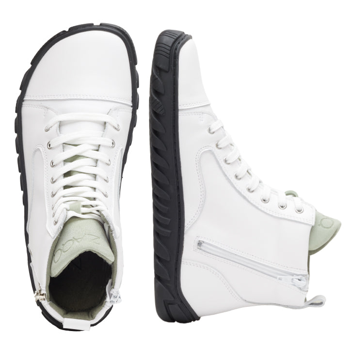 Die QENDO White High-Top-Sneaker von ZAQQ sind mit Ultragrip-Sohlen ausgestattet, die für hervorragenden Halt sorgen. Diese stylischen Schuhe verfügen über seitliche Reißverschlüsse und weiße Schnürsenkel und werden von der Seite und von oben betrachtet, wodurch das hellgrüne Innenfutter hervorgehoben wird.