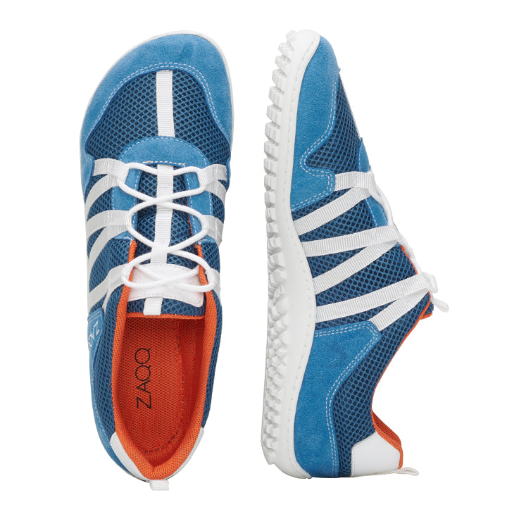 Die RIQ Blue Sneaker von ZAQQ sind ein Paar sportliche Schuhe mit blauem Obermaterial und weißen Schnürsenkeln und Sohlen. Sie verfügen über orangefarbene Innenteile und atmungsaktive Mesh-Einsätze für mehr Komfort. Ein Schuh wird von oben präsentiert, während der andere seitlich positioniert ist, was das dynamische Design hervorhebt.