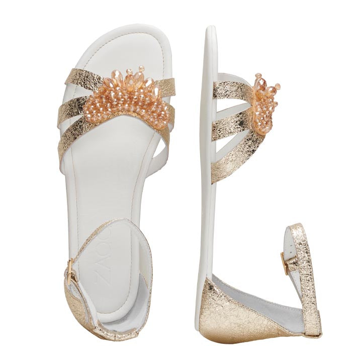 Die QISELLE Gold Sandalen von ZAQQ verfügen über elegante goldene Riemen, die mit dekorativen Perlenverzierungen verziert sind, die auf dem vorderen Riemen ein florales Muster bilden. Sie sind mit einer weißen Sohle und einem praktischen Reißverschluss auf der Rückseite ausgestattet, was die berühmte Handwerkskunst von ZAQQ unterstreicht.