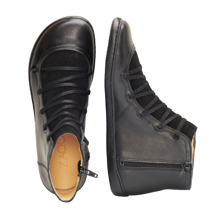 Wir präsentieren den Quechee Black von ZAQQ: ein Paar elegante schwarze Schuhe aus Nappaleder mit seitlichen Reißverschlüssen und Schnürung vorne. Der linke Mid-Cut-Sneaker ist von oben abgebildet und zeigt die Innensohle, während der rechte Schuh elegant von der Seite präsentiert wird.