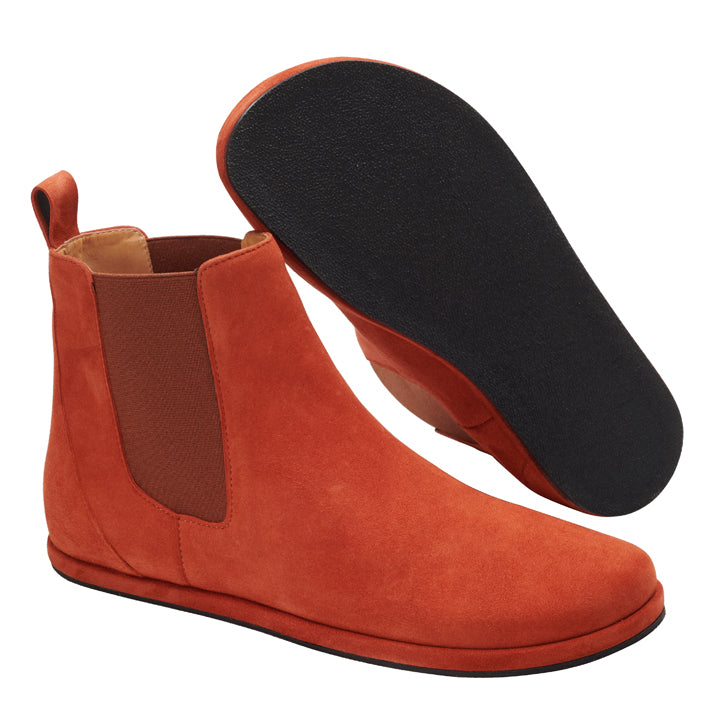 Ein Paar EQUITY Terra Chelsea-Stiefel von ZAQQ besteht aus Veloursleder in gebranntem Orange mit schwarzen Sohlen, seitlichen elastischen Einsätzen und Laschen. Ein Stiefel steht aufrecht, um die Seitenansicht zu zeigen, während der andere die Sohle betont. Diese Stiefel wurden für Stil und Komfort gefertigt und sind eine unverzichtbare Ergänzung für jede Garderobe.