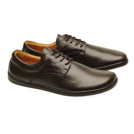 Ein Paar PEAQ Dark Brown-Schuhe von ZAQQ im klassischen Business-Casual-Design mit Schnürsenkeln und glatter Oberfläche. Diese eleganten Schuhe haben eine dünne Sohle und sind in Dunkelbraun gehalten, während das Innenfutter in einem helleren Braun einen schönen Kontrast bildet.