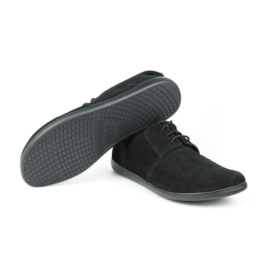 Der PIQUANT Velours Black von ZAQQ wird mit einem Sneaker stehend und einem seitlichen Sneaker präsentiert, der die strukturierte Sohle zur Schau stellt. Das Design ist schlicht und lässig mit Schnürsenkeln.