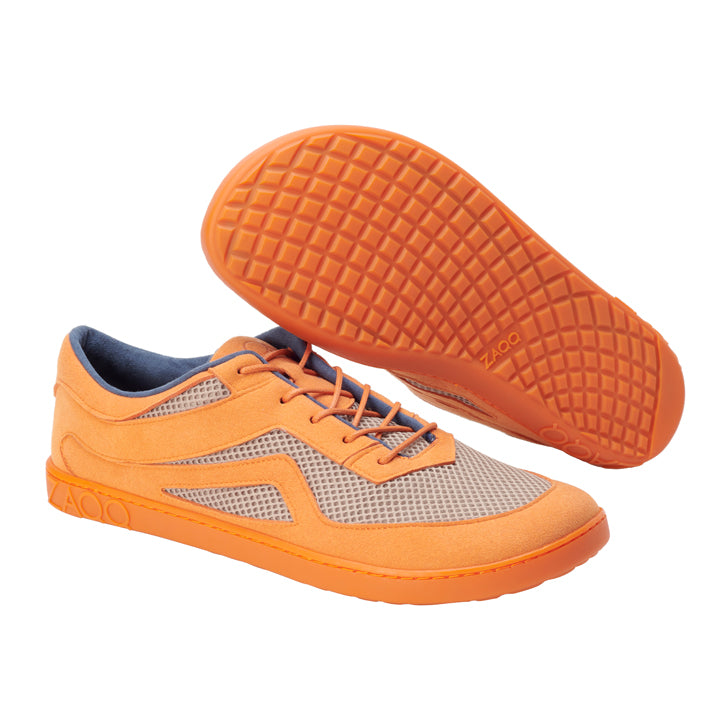 Ein Paar QYNLEE Orange-Schuhe von ZAQQ besteht aus Netzgewebe und Gummisohlen. Ein Schuh ist aufrecht abgebildet, während der andere geneigt ist, um das Muster der Sohle zu zeigen. Die Schnürsenkel und der Besatz sind ebenfalls orange, was das Design ergänzt und die Atmungsaktivität für Laufbegeisterte verbessert.