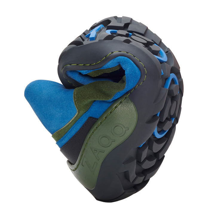 Nahaufnahme eines flexiblen, spiralförmig gerollten ZAQQ SQOUT Blue Green Waterproof Outdoor-Schuhs. Er verfügt über eine robuste, schwarz-blaue Sohle mit einem Obermaterial aus grün-blauem Stoff. Der Markenname ZAQQ ist auf der Seite sichtbar und hebt die langlebige TERRA-Sohle hervor.