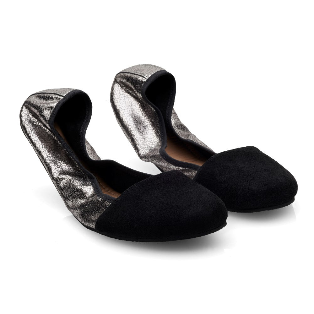 Ein Paar Ballerinas für Damen von ZAQQ, genannt TWIST Derby Black, mit metallisch silbernen Seiten und velourslederähnlichen Zehenkappen. Sie sind schräg vor einem weißen Hintergrund positioniert.